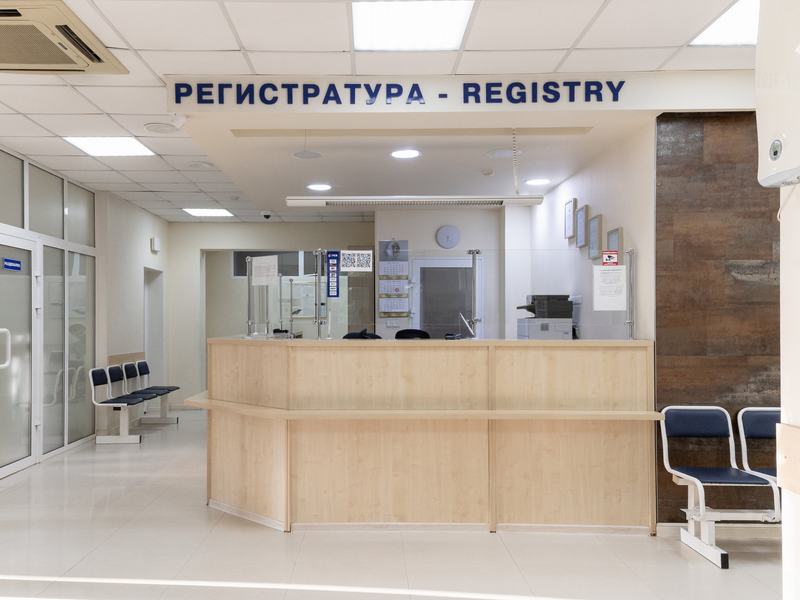 Стойка регистратуры со светлой столешницей под вывеской «Регистратура — Registry»